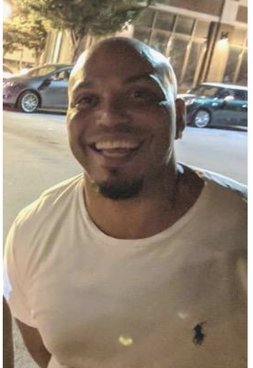 Man standing on street at night, smiling a camera